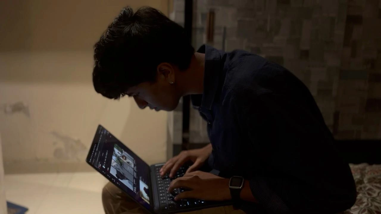 Melvis working at a laptop in low light