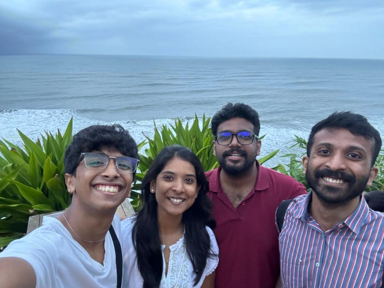 Four friends on a beach with the sea behind them