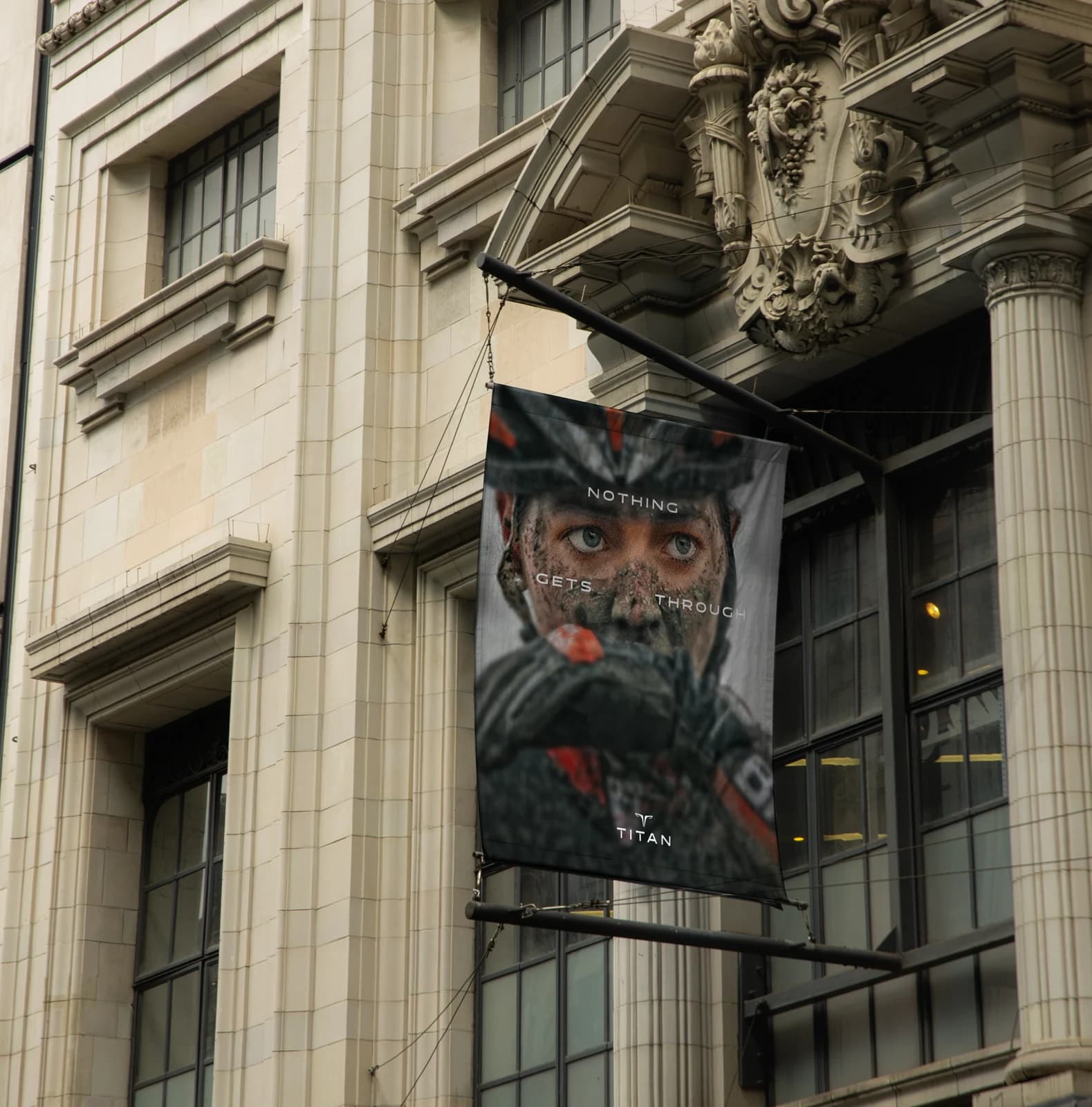 The same campaign as a fabric banner hung from a stone building, a mud-covered rider's eyes above the line