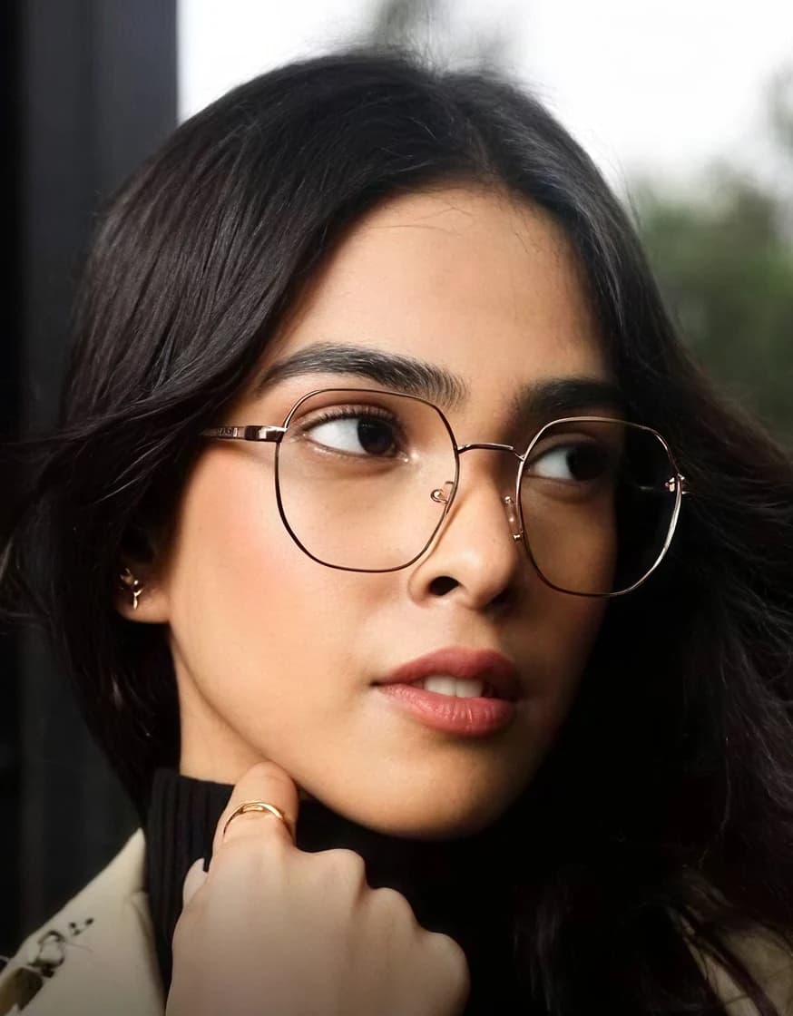 Thin metal optical frames worn against a window, daylight through the lenses