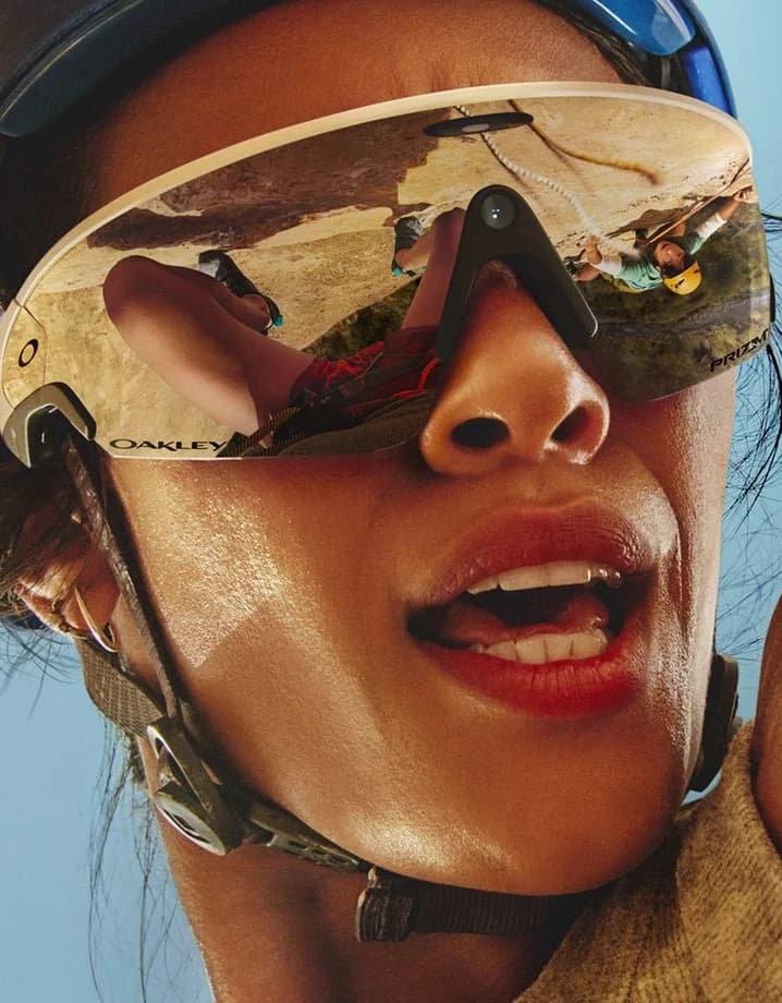 A single-lens shield visor close up, climbers mirrored across the whole lens